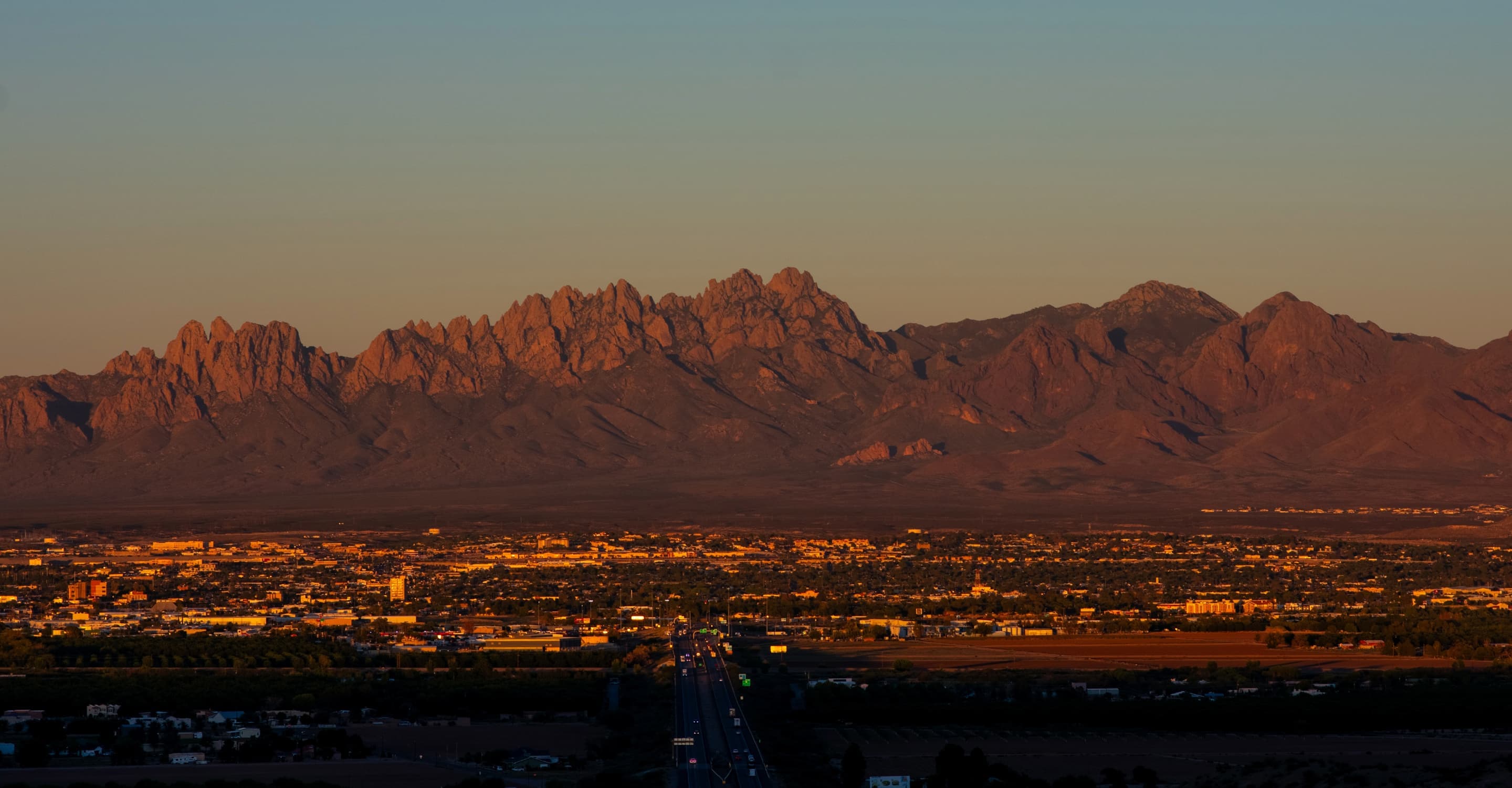 Southwestern mountain range at dusk over a lit valley
